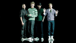 four men standing on black surface
