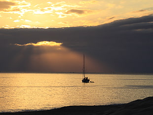 boat on sea water under cloudy sky during sunrise
