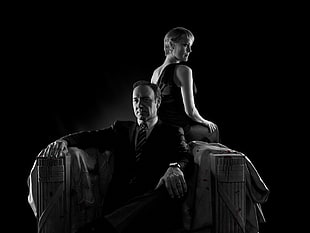 grayscale photo of man in suit sitting on chair beside woman in sleeveless dress HD wallpaper
