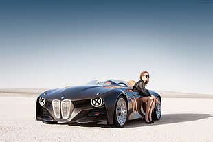 female sitting on black sports convertible on desert