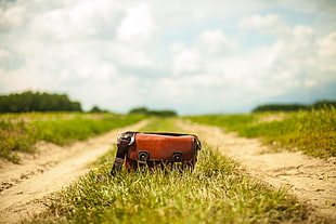 red leather sling bag on grass road HD wallpaper