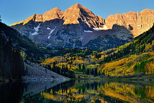 mountain near body of water and tall trees at daytime, maroon bells