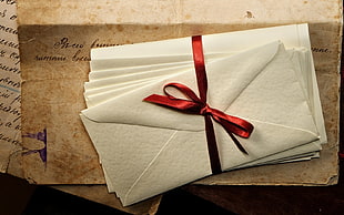 pile of white envelopes with red ribbon
