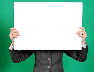 person holding white blank board covering face