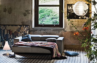 gray sofa bed with blanket near black framed window