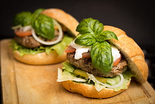 two hamburgers with green mint leaves on top