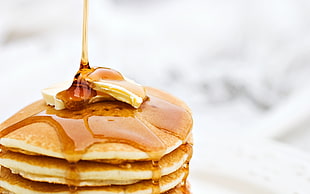 selective focus photography of stack of pancake with butter and maple syrup