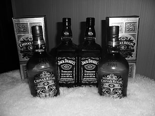 Grayscale photo of  two Jack Daniel and Chivas Regal