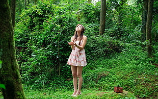 woman wearing white and pink tank mini dress standing beside the tree during daytime