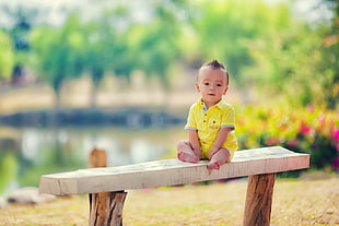 boy wearing yellow button-up shirt sitting on brown wooden bench