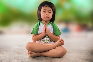 child wearing green and white shirt meditating