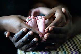 two person holding baby's feet with wedding ring set