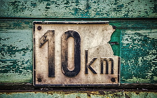 10 KM signage mounted on green painted wall