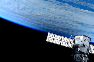 white and gray satellite on top of earth