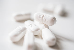 white medicine pills on white surface