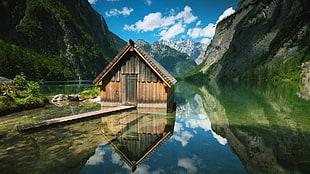 brown wooden house on body of water near mountain HD wallpaper