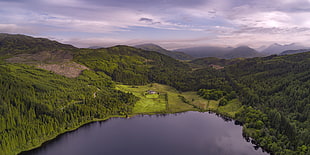 aerial photography of lake surrounded with land and mountains under gray sky