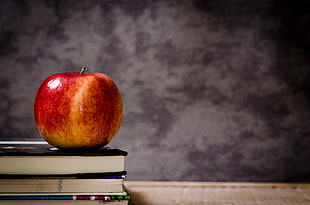 red and yellow apple on books