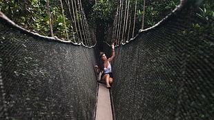 photograph of woman seating in front of hanging bridge