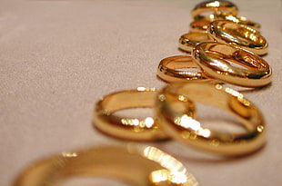 selective focus photography of gold-colored ring lot on beige textile