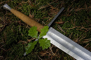 gray and brown metal tool, sword, grass