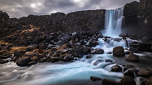 time lapse photography of water falls surrounded by stones under heavy clouds, iceland HD wallpaper