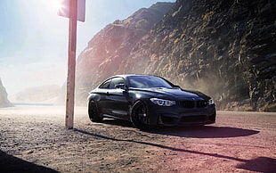 black BMW M4 near brown post and rock mountain