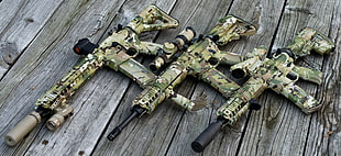 three green camouflage printed guns on top of brown wooden surface