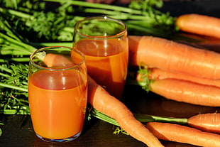 closeup photography of pile of carrots and two carrot juices