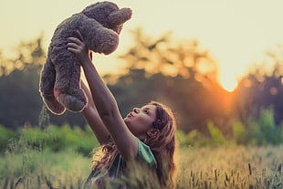 woman in a field holding up a teddy bear during golden time HD wallpaper