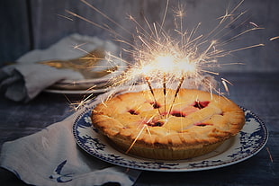 time lapse photography of lighted sparkler candles on top of baked pie