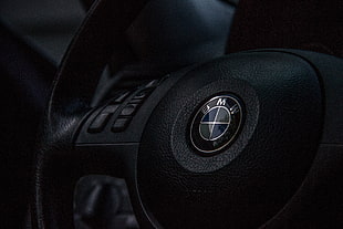 closeup photography of black BMW multi-function steering wheel