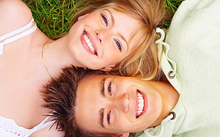man and woman lying on grass field