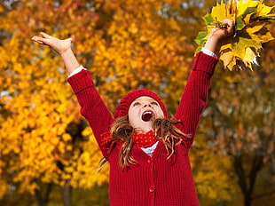 girl wearing knit red sweater with knit red cap under maple tree