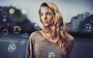 Woman in brown one shoulder top surrounded by bubbles