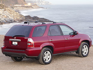 red SUV parked on seashore during daytime