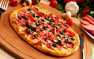 pepperoni with black olive pizza on brown wooden tray with knife and fork