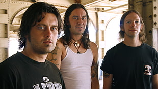 three men in white and black shirts looking towards the camera