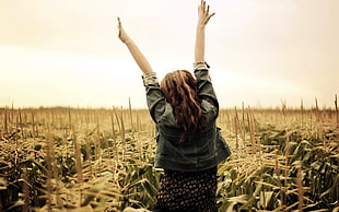 back vie of woman raising her both hands high at the fields