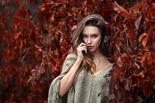 shallow focus of woman in gray sweater beside brown plants