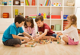 two boys and two girls playing with wooden blocks