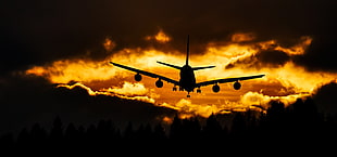 silhouette of plane flying in the sky during orange sunset