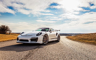 white sports coupe on gray concrete road between dried grass fields taken during day time HD wallpaper