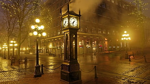 brown clock near road and lampposts