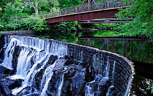 photo of water dam with brown metal bridges and green trees