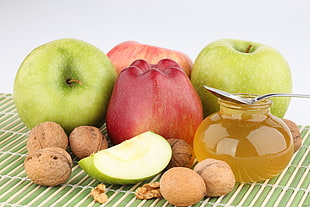 photography of green and red apples beside honey jar filled with brown liquid