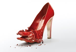 unpaired broken red leather platform stilettos on white background