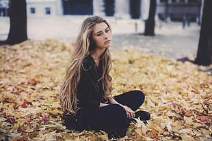woman wearing black long-sleeved shirt and pants sitting on dry leaves