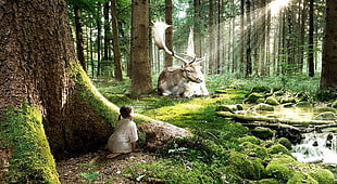 child sitting beside tree facing moose lying on grass, nature, children, animals, fictional