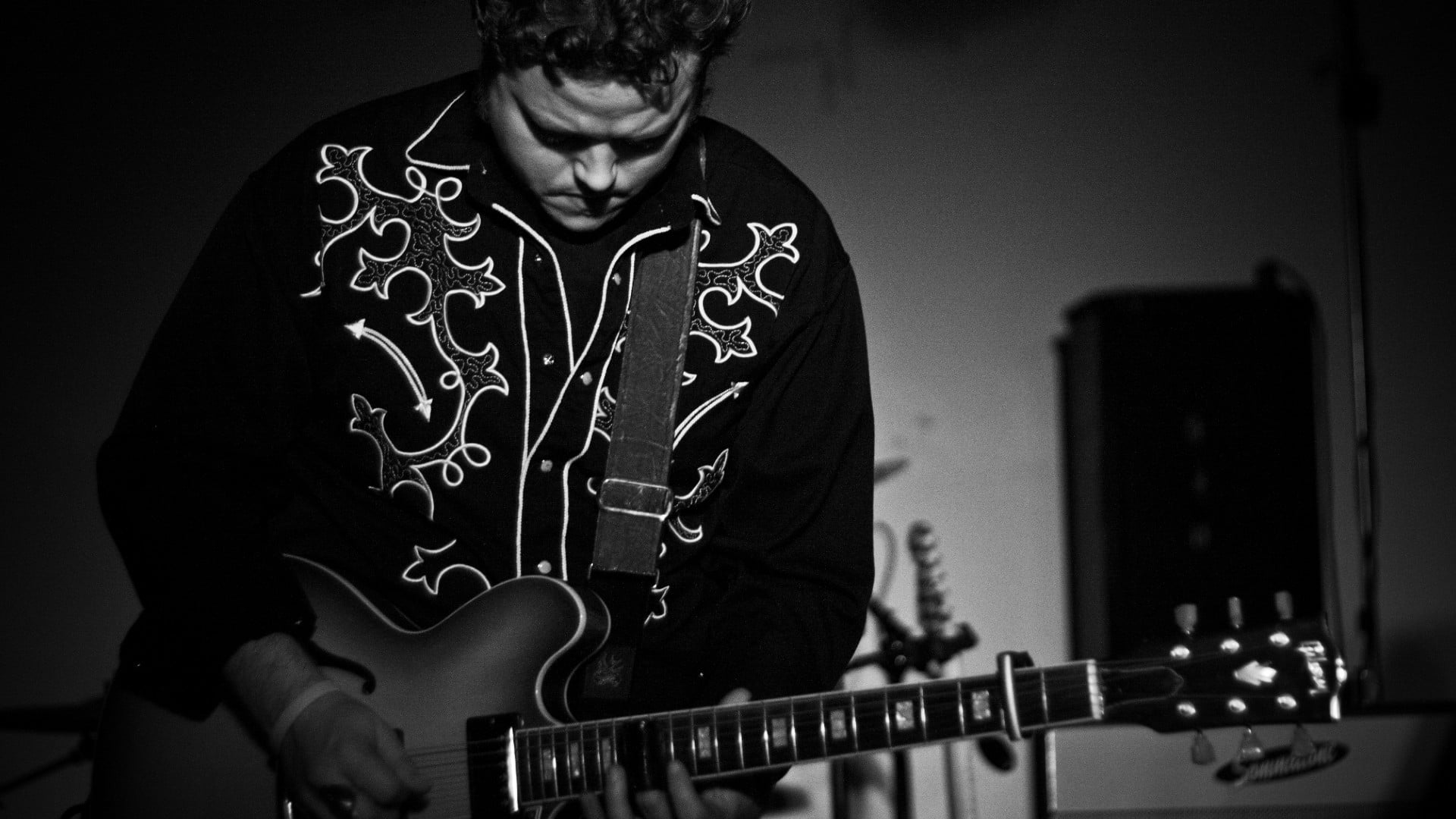 grayscale photo of man playing guitar